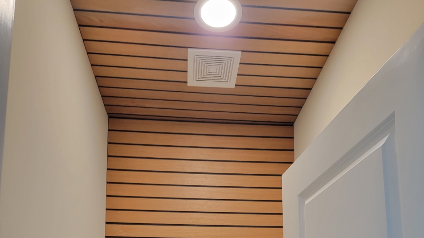 Fluted oak slat wall continuing across the ceiling